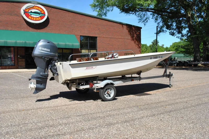 Slide: The Image of 1976 Boston Whaler 15 boat with Yamaha motor on trailer, parked outside marine store. - 6