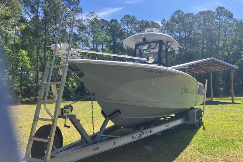 The Image of 2020 Sea Hunt Gamefish 27 boat on trailer, surrounded by trees and a shed. - 22