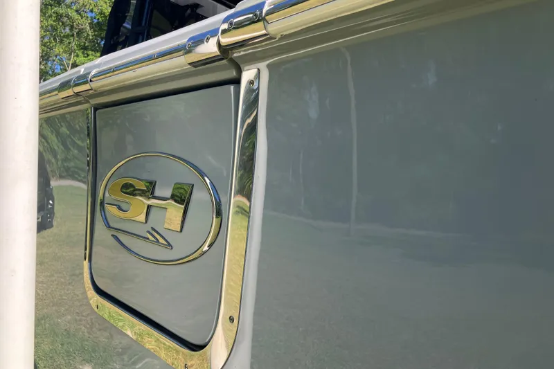 Slide: The Image of 2020 Sea Hunt Gamefish 27 boat emblem with chrome detailing in outdoor setting. - 75