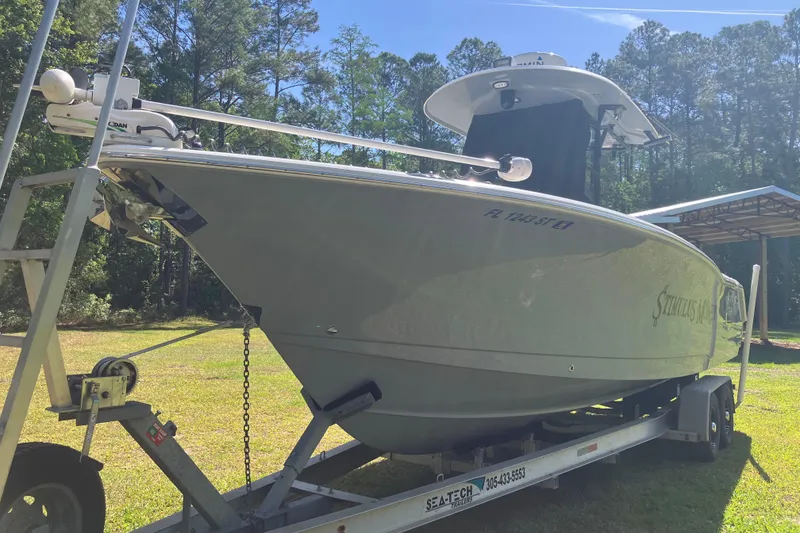 Slide: The Image of 2020 Sea Hunt Gamefish 27 boat on trailer, parked outdoors with trees in background. - 77