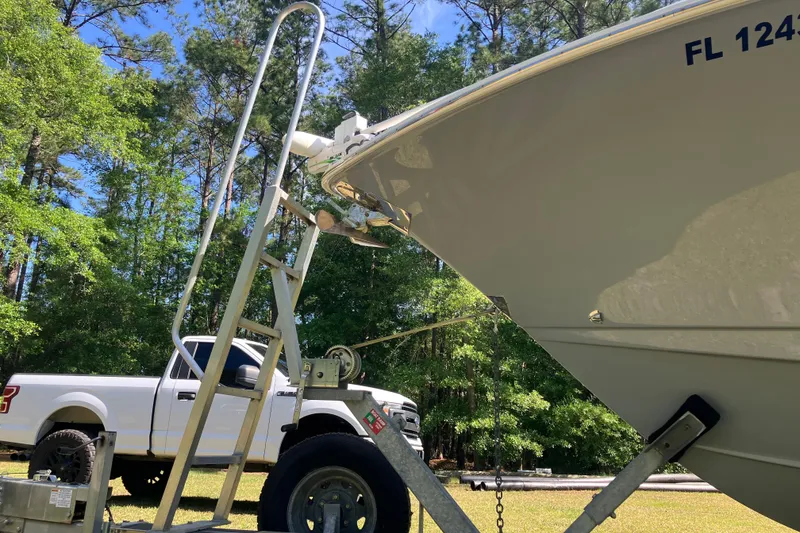 Slide: The Image of 2020 Sea Hunt Gamefish 27 on trailer beside white truck in wooded area. - 78