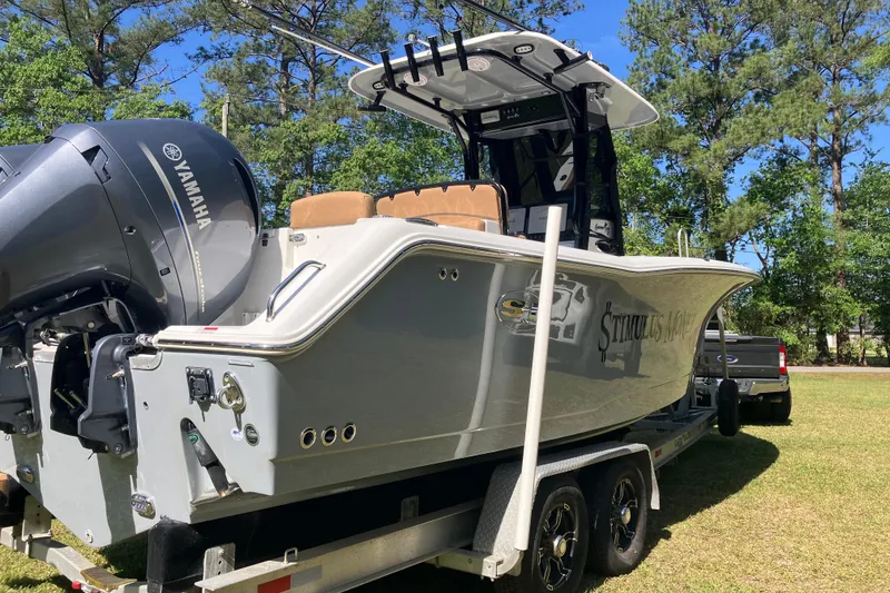 Slide: The Image of 2020 Sea Hunt Gamefish 27 boat on trailer, featuring Yamaha engine, parked outdoors. - 92