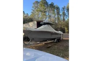 Slide: The Image of 2020 Sea Hunt Gamefish 27 boat covered and parked outdoors near trees. - 97