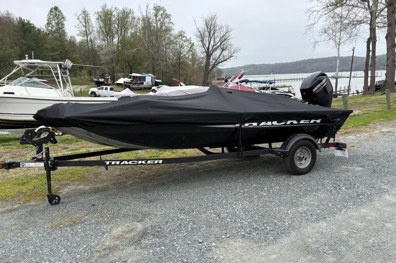 Slide: The Image of 2025 Tracker Pro 170 boat on trailer, covered, parked near a lake. - 2