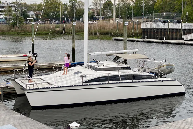 The Image of A 1991 PDQ 36 catamaran docked, with two people on deck, in a marina setting. - 0