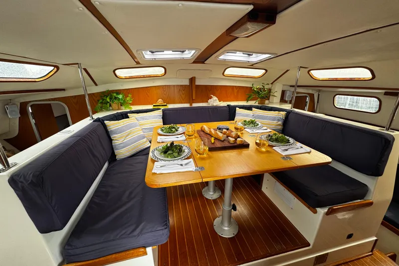Slide: The Image of Cozy dining area inside a 1991 PDQ 36 boat, featuring a wooden table and cushioned seating. - 11