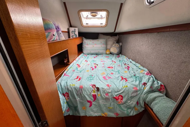 Slide: The Image of Cozy boat cabin with mermaid-themed bedding, featuring plush toys and wooden shelves. - 19