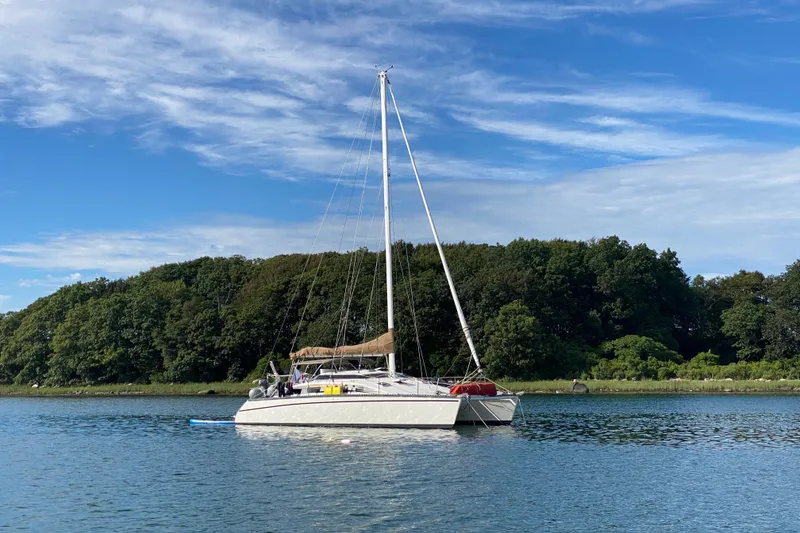 Slide: The Image of Sailboat PDQ 36 (1991) anchored on a serene lake with lush green trees. - 2