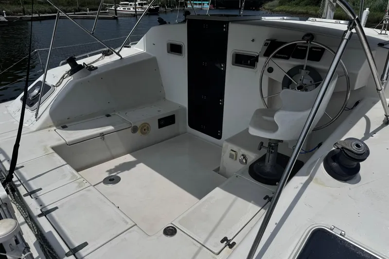 Slide: The Image of 1991 PDQ 36 sailboat cockpit with steering wheel and seating, docked by the water. - 7