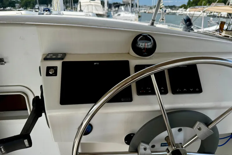 Slide: The Image of Steering wheel and dashboard of a 1991 PDQ 36 boat, docked at a marina. - 8