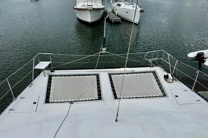 Slide: The Image of 1991 PDQ 36 catamaran deck with netting, docked near other boats. - 9