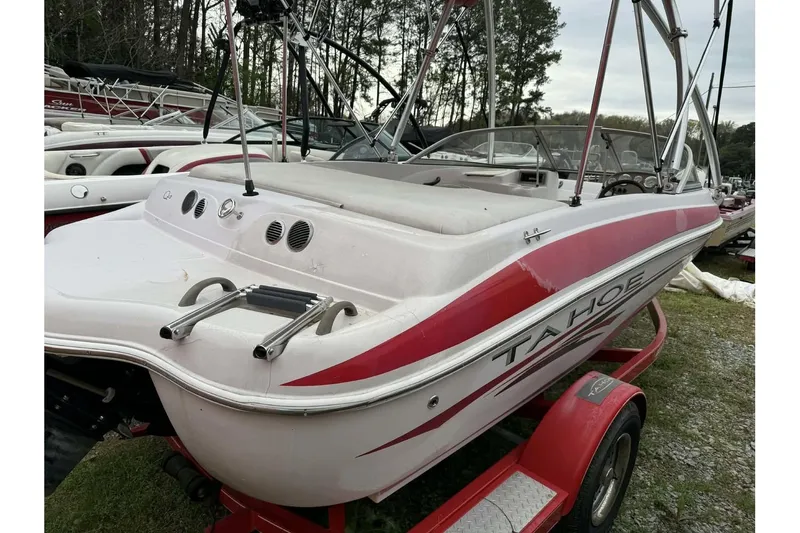 Slide: The Image of 2005 Tahoe Q4 Sport boat with red accents on a trailer, parked outdoors. - 11