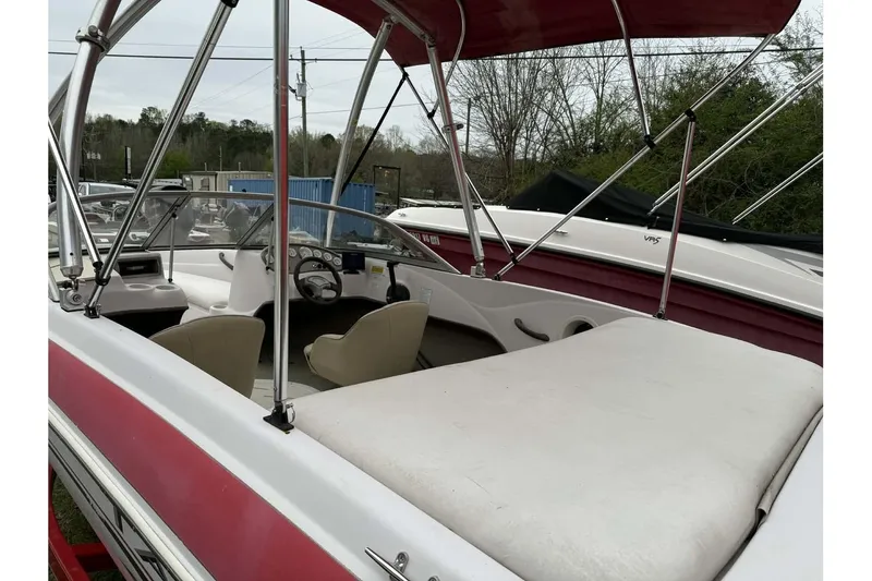 Slide: The Image of 2005 Tahoe Q4 Sport boat with red canopy and white seating, parked outdoors. - 2