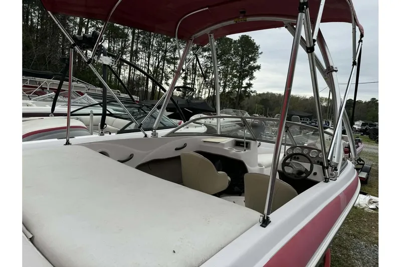 Slide: The Image of 2005 Tahoe Q4 Sport boat with red canopy and white interior, parked outdoors. - 4