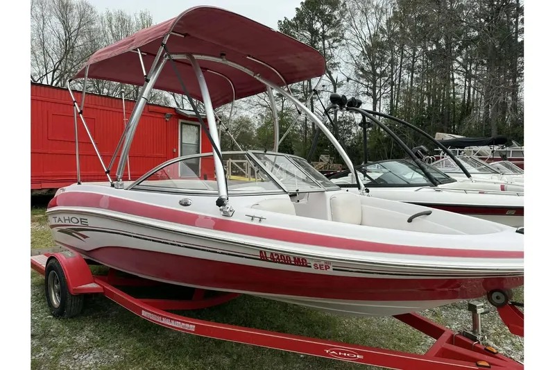 Slide: The Image of 2005 Tahoe Q4 Sport boat with red canopy on trailer, parked outdoors. - 5
