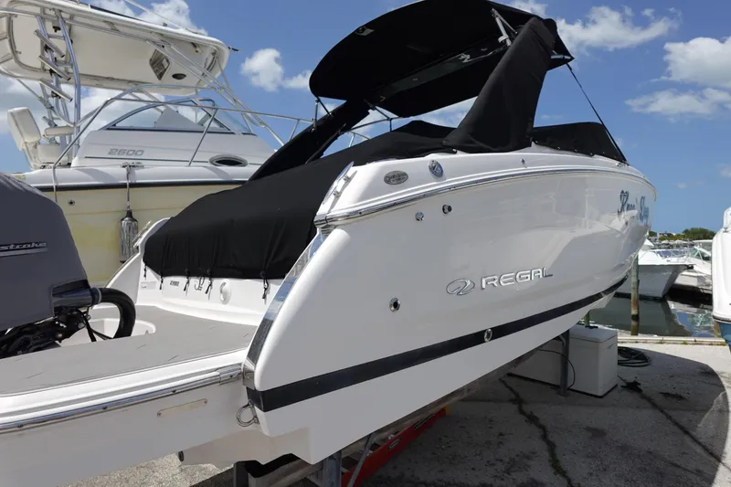 Slide: The Image of 2021 Regal 23 OBX boat docked, featuring sleek design and black canopy. - 2