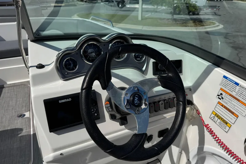 Slide: The Image of 2023 NauticStar 243 DC boat dashboard with steering wheel and control panel. - 13