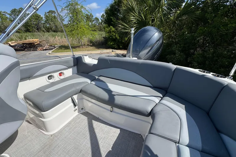 Slide: The Image of 2023 NauticStar 243 DC boat interior with gray seating and lush greenery background. - 16