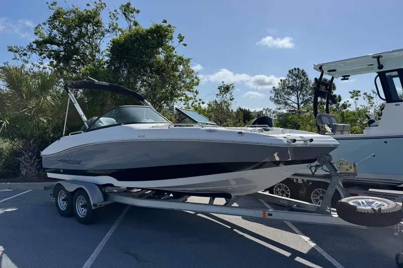 The Image of 2023 NauticStar 243 DC boat on trailer, parked outdoors under clear sky. - 1