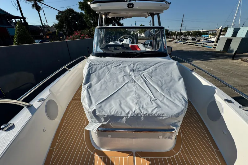 Slide: The Image of 2025 Nimbus Tender 8 boat with covered seating area, docked under clear skies. - 20