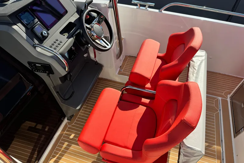 Slide: The Image of Red seats and steering console of 2025 Nimbus Tender 8 boat, featuring modern design. - 24