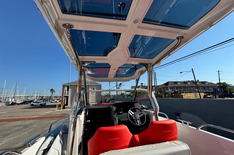 Slide: The Image of 2025 Nimbus Tender 8 boat interior with red seats and glass roof, dockside view. - 25