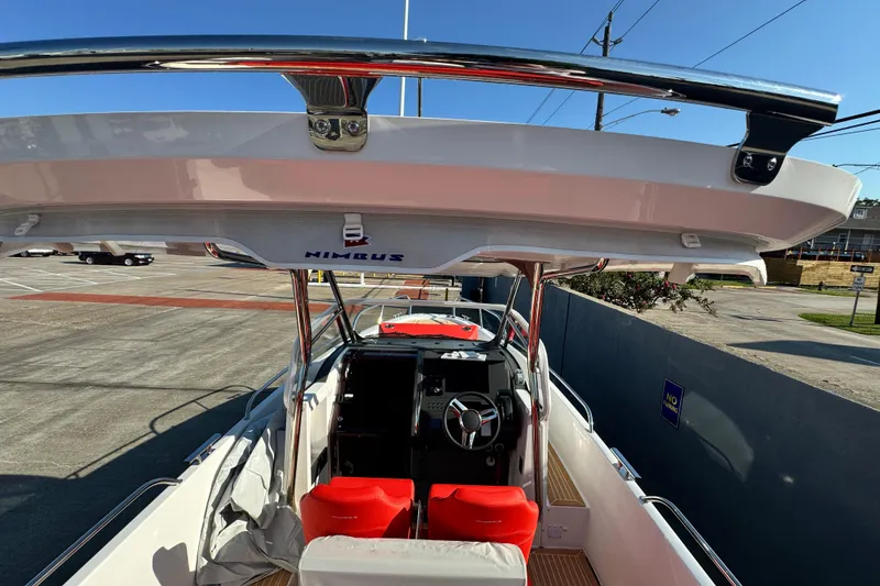 Slide: The Image of 2025 Nimbus Tender 8 boat interior with red seats and steering wheel, parked outdoors. - 26