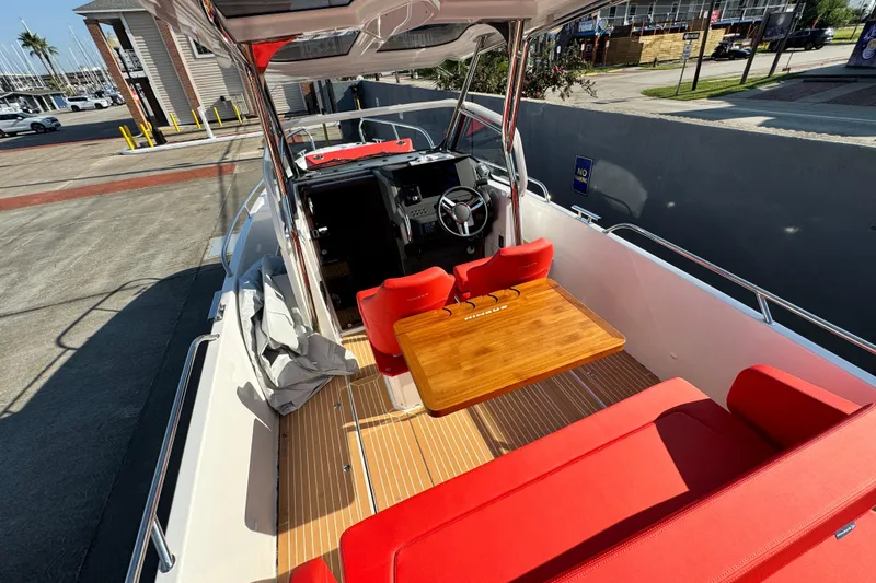 Slide: The Image of 2025 Nimbus Tender 8 boat with red seating and wooden table, docked at marina. - 27