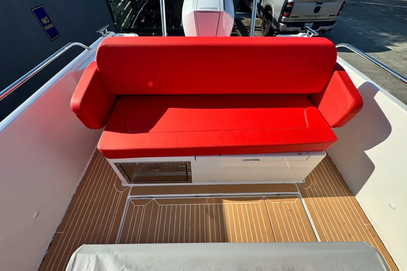 Slide: The Image of Red cushioned seating on 2025 Nimbus Tender 8 boat deck, with wood-patterned flooring. - 28