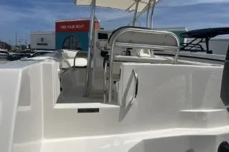 Slide: The Image of 2022 Sailfish 242 CC boat interior with seating and helm, under clear blue sky. - 9