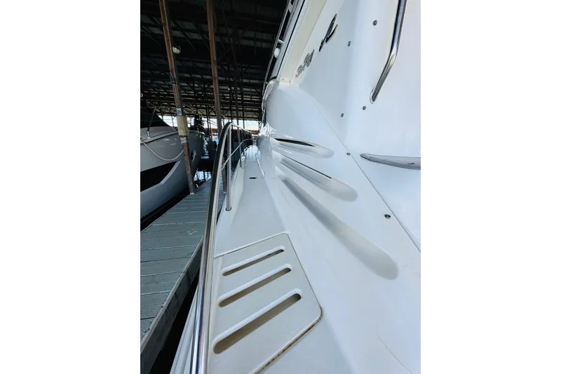 Slide: The Image of 2000 Sea Ray 400 Sedan Bridge yacht docked, showcasing sleek white exterior and stainless steel railings. - 11