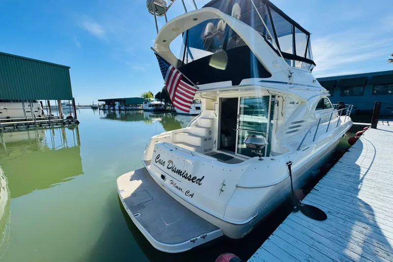 Slide: The Image of 2000 Sea Ray 400 Sedan Bridge yacht docked, rear view with American flag. - 14