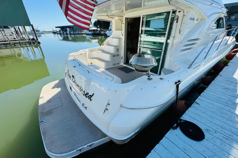 Slide: The Image of 2000 Sea Ray 400 Sedan Bridge docked, featuring a spacious deck and American flag. - 15