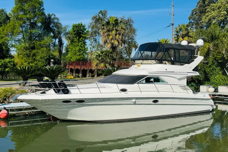 Slide: The Image of 2000 Sea Ray 400 Sedan Bridge yacht docked in a lush, tropical setting. - 2