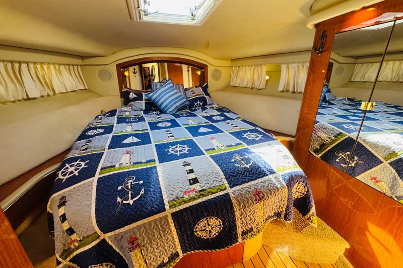 Slide: The Image of Cozy cabin interior of 2000 Sea Ray 400 Sedan Bridge with nautical-themed bedding. - 55