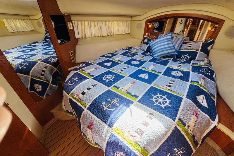 Slide: The Image of Cozy cabin interior of 2000 Sea Ray 400 Sedan Bridge with nautical-themed bedding. - 56
