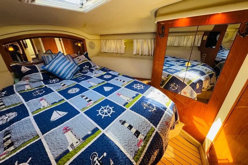 Slide: The Image of Cozy bedroom in 2000 Sea Ray 400 Sedan Bridge with nautical-themed bedding and mirrored closet. - 57