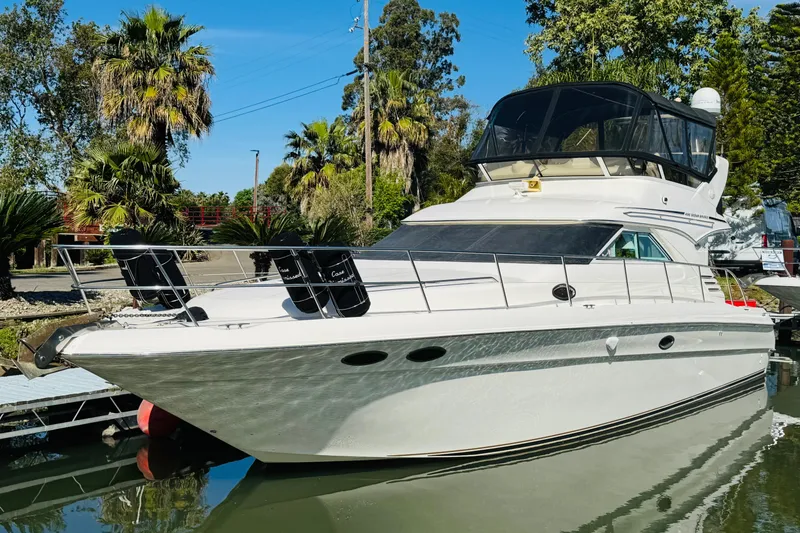 Slide: The Image of 2000 Sea Ray 400 Sedan Bridge yacht docked in a scenic marina setting. - 77