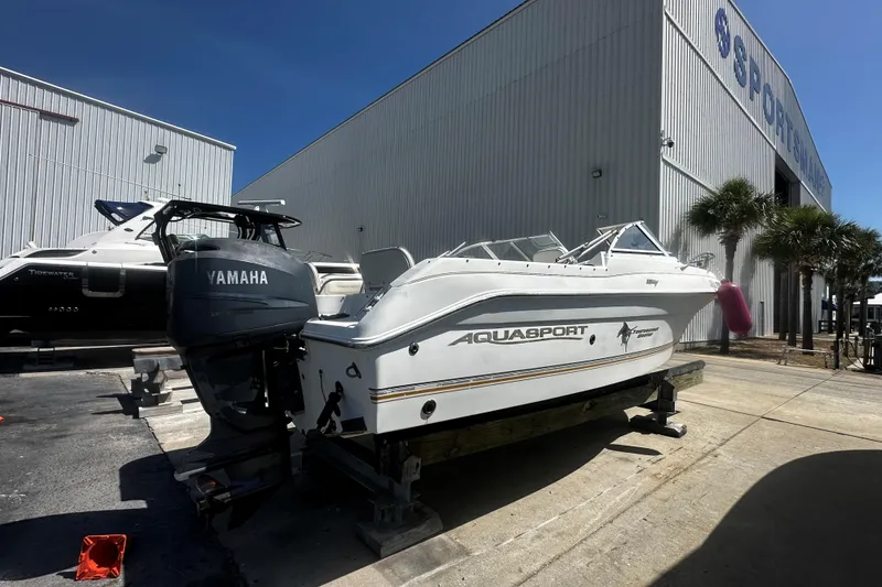 Slide: The Image of 2004 Aquasport 215 Osprey Sport boat with Yamaha engine, parked outside a storage facility. - 3