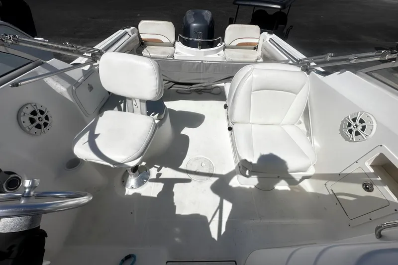 Slide: The Image of 2004 Aquasport 215 Osprey Sport boat interior with white seating and steering wheel. - 8