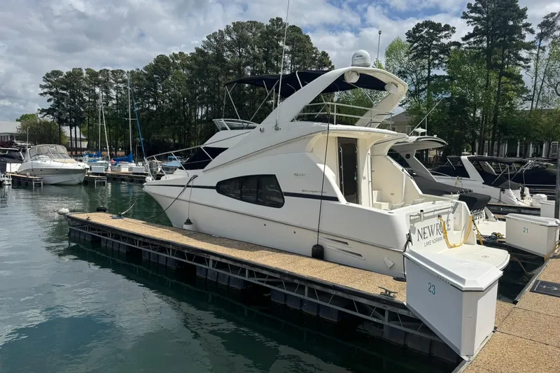 Slide: The Image of 2005 Silverton 330 Sport Bridge yacht docked at a marina, surrounded by trees and calm water. - 2