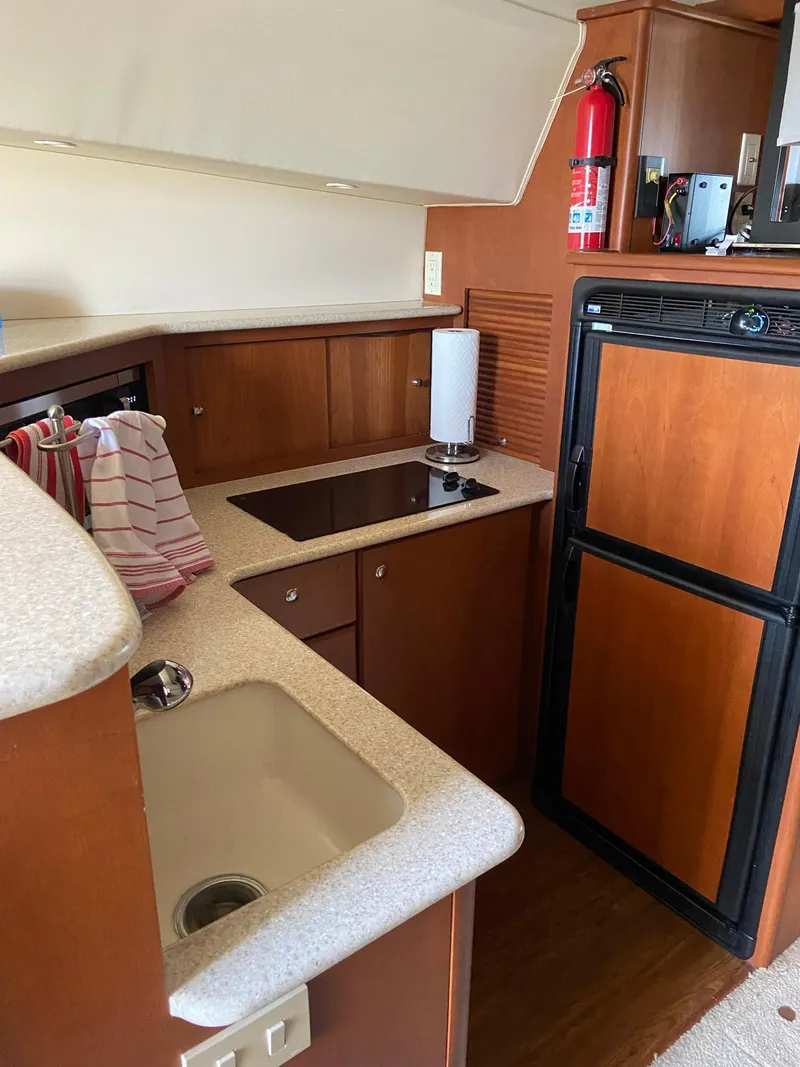 Slide: The Image of 2005 Silverton 330 Sport Bridge helm with white seating and marina view. - 20