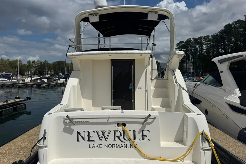 Slide: The Image of 2005 Silverton 330 Sport Bridge yacht docked with chairs and American flag. - 5
