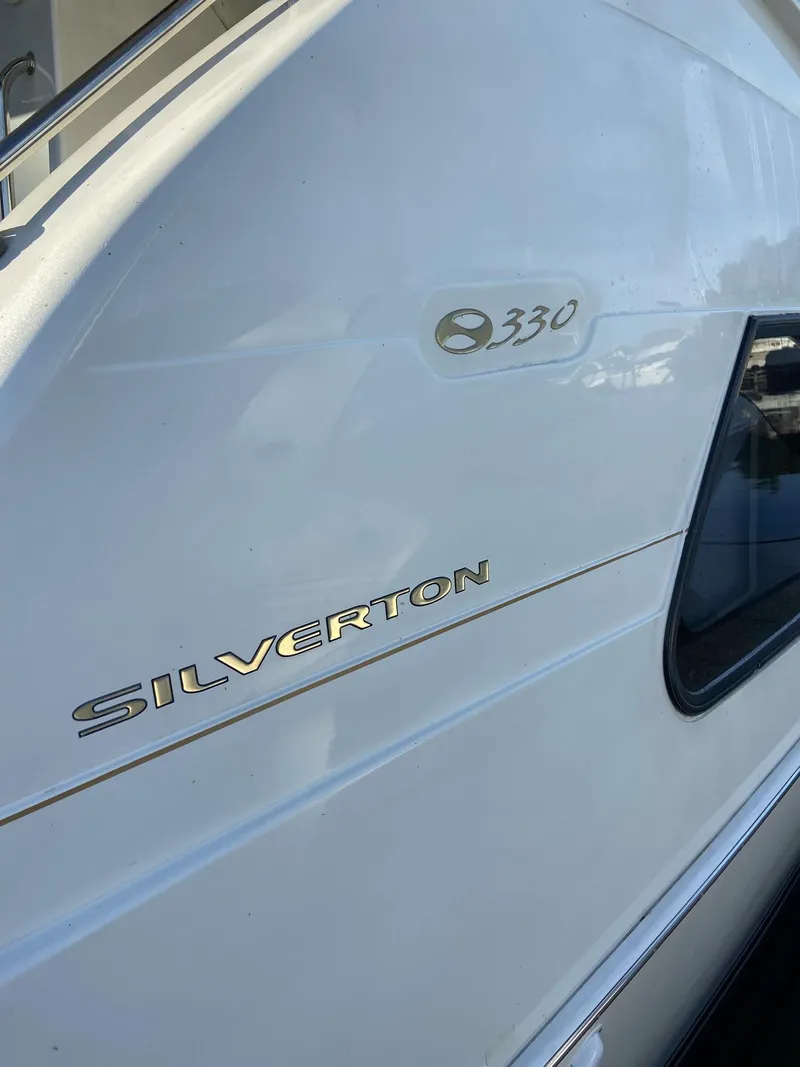 Slide: The Image of 2005 Silverton 330 Sport Bridge yacht docked at a marina with trees in the background. - 6