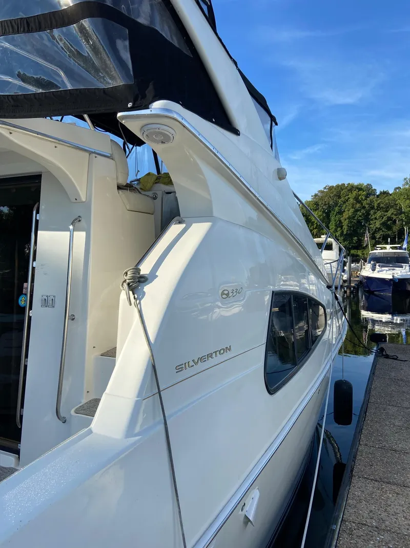 Slide: The Image of 2005 Silverton 330 Sport Bridge yacht docked at a marina, surrounded by other boats. - 7