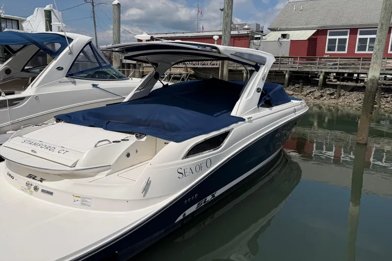 Slide: The Image of 2015 Sea Ray SLX 350 boat docked, covered with blue canvas, in a marina setting. - 1