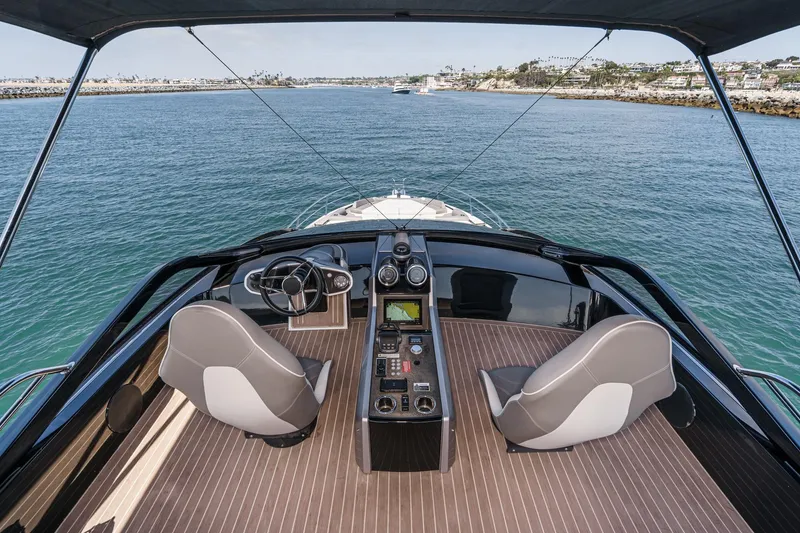 Slide: The Image of 2023 Sunseeker 65 Sport Yacht helm with dual seats, steering wheel, and navigation controls. - 15