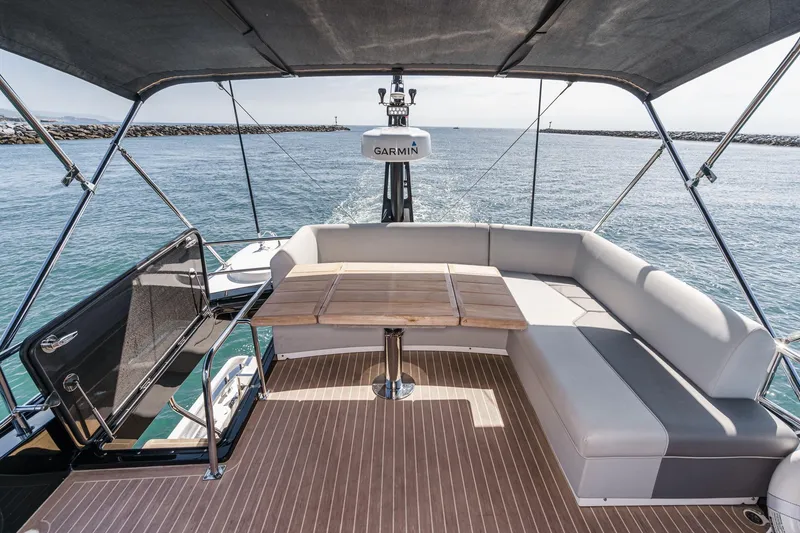 Slide: The Image of 2023 Sunseeker 65 Sport Yacht deck with seating and table, overlooking the ocean. - 19