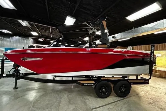The Image of Red 2023 Nautique Super Air Nautique G23 boat on trailer in showroom. - 0