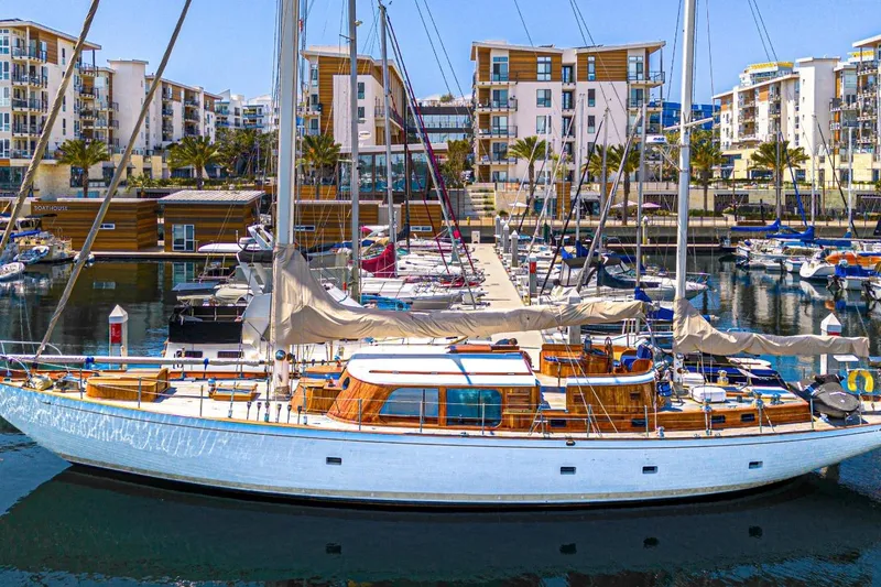 Slide: The Image of 1961 Vic Franck Custom yacht docked in a modern marina with surrounding buildings. - 0
